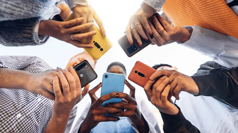 Image of five gen z'ers huddled together on their mobile phones